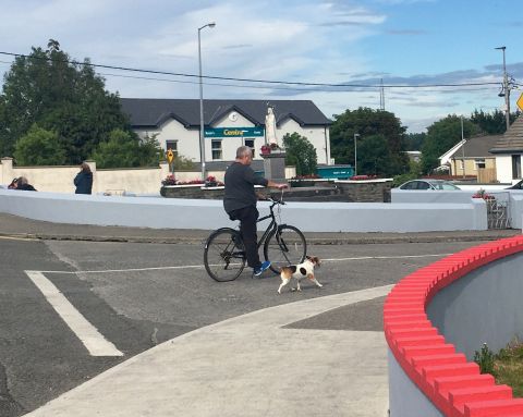 Man on bicycle walking dog on lead, Ennis town